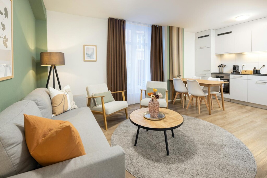 Living room with sage green wall and open kitchen at STAYY N&ordm;7 in Zurich