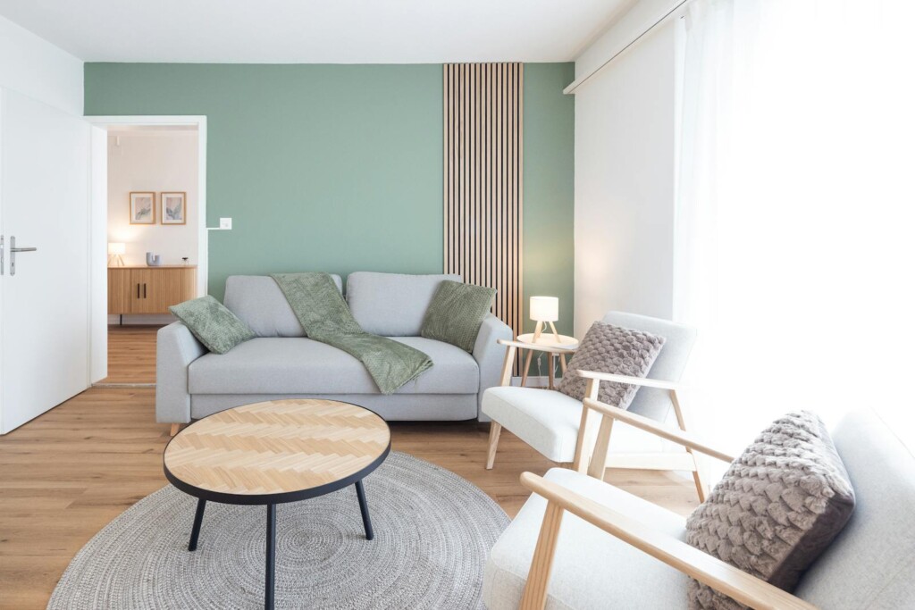 Living room with sage green wall at STAYY Reben Suites in Illnau-Effretikon